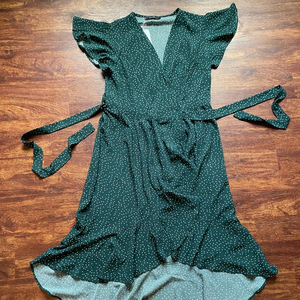 Dark green flirty wrap dress with white polka dots and a ruffled high-low hem